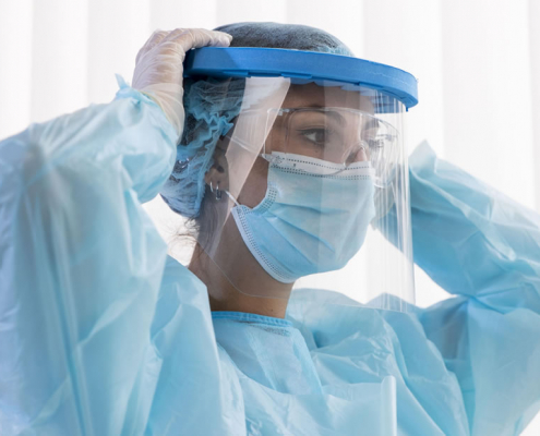 Medico utilizando bata de protección, guantes, monogafas, pantalones, polainas, mascarilla y gorro en tela desechable